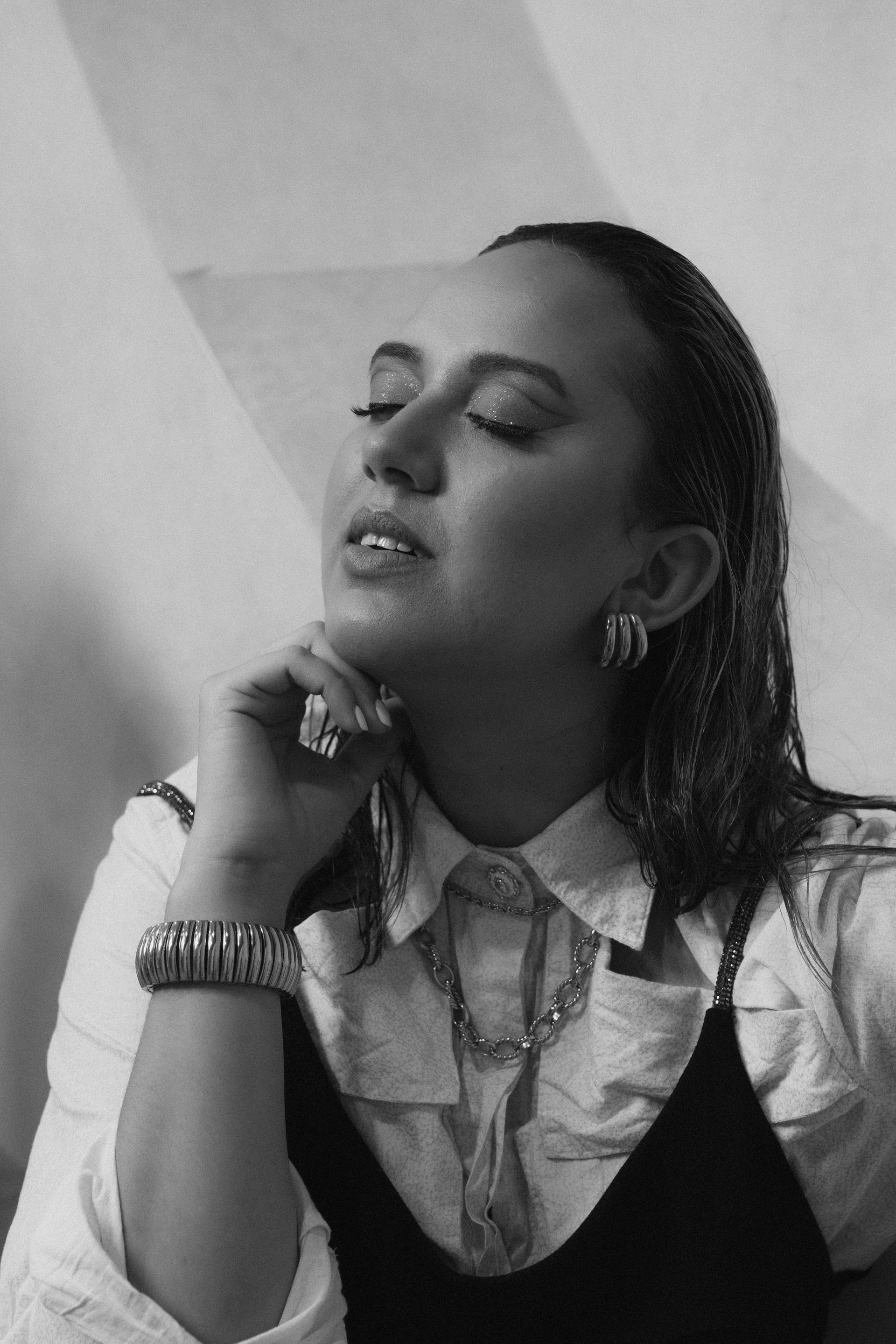 A black and white photo of a woman wearing a watch and earrings.
