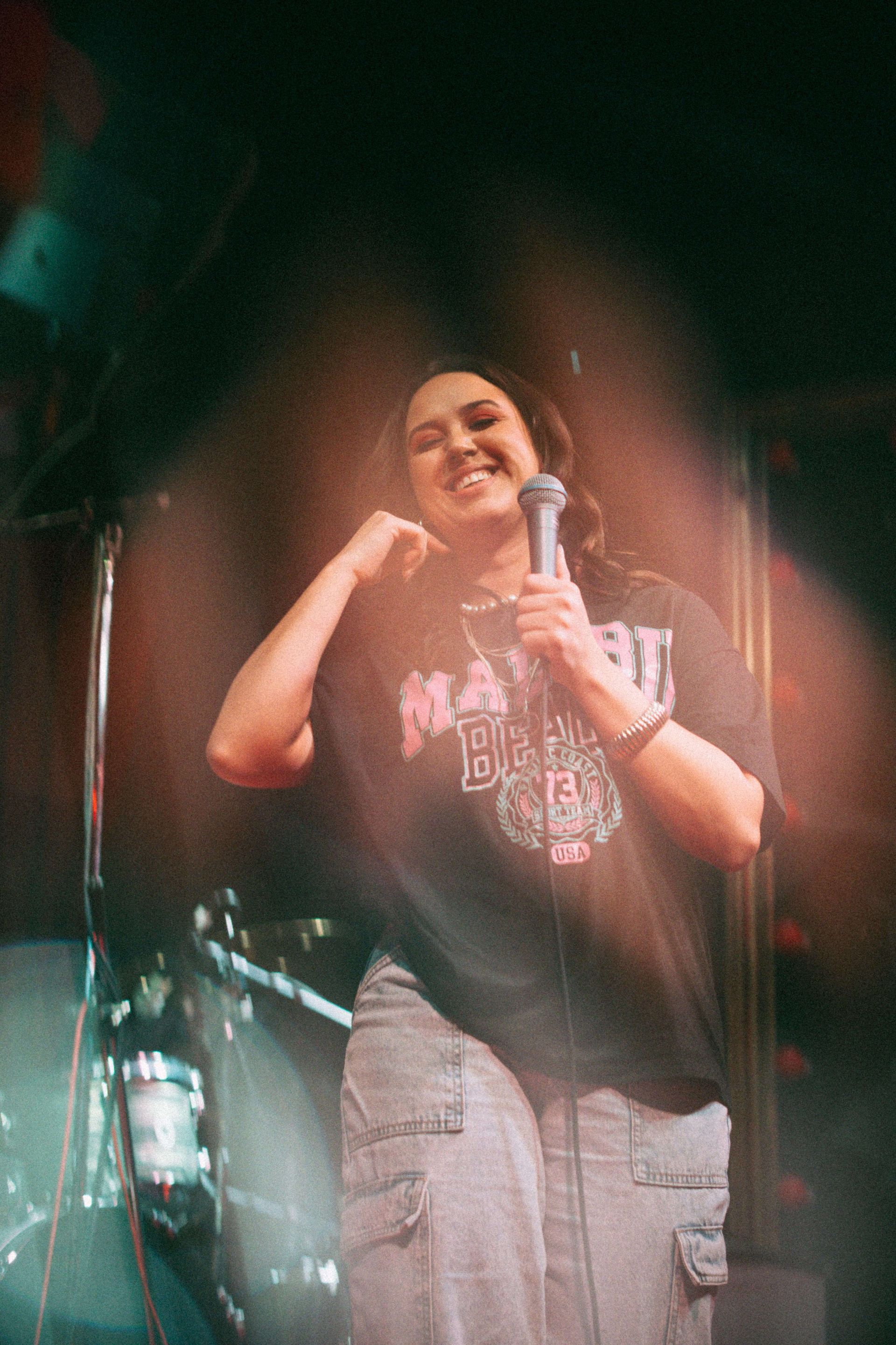 A woman is singing into a microphone on a stage.