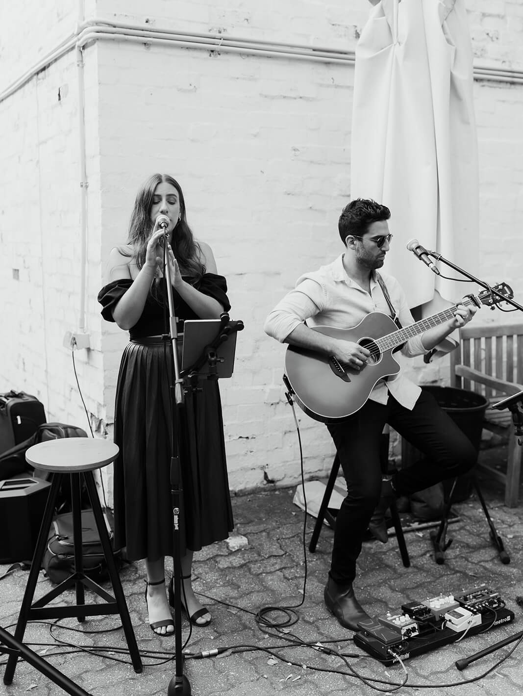 A man is playing a guitar and a woman is singing into a microphone.