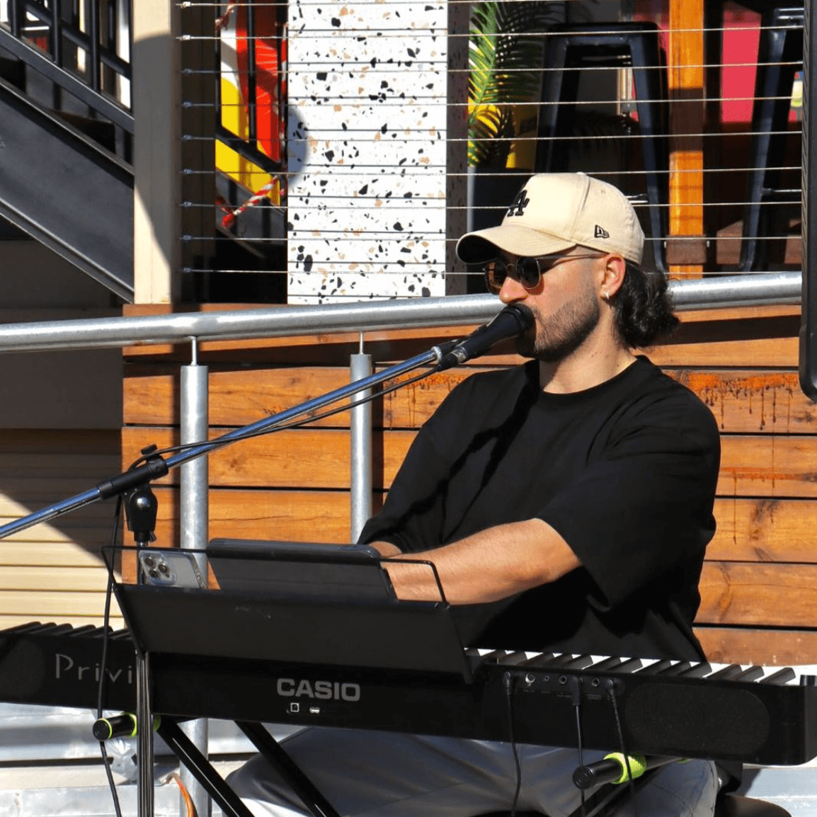 A man is singing into a microphone while playing a casio keyboard