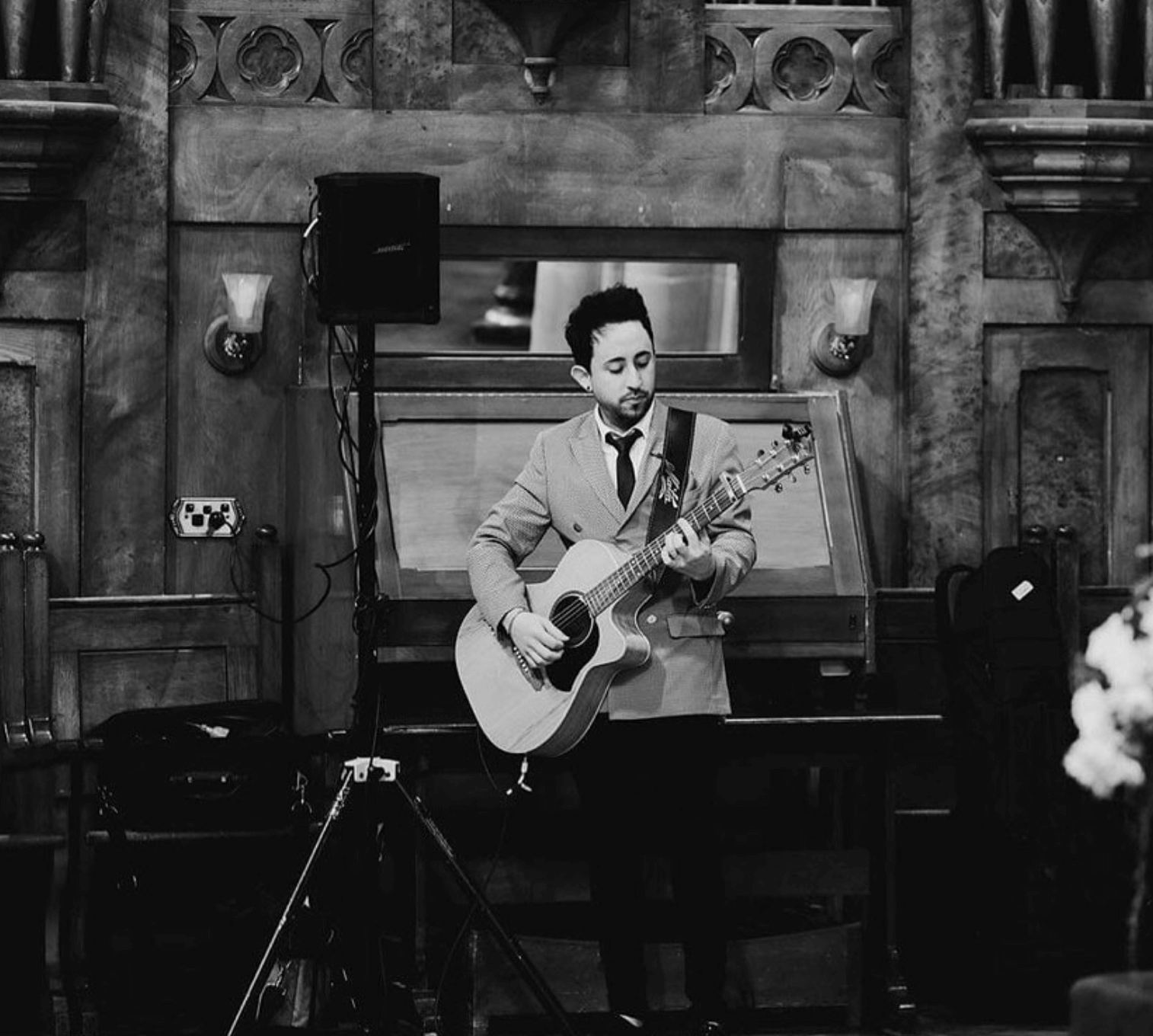 A man in a suit and tie is playing an acoustic guitar