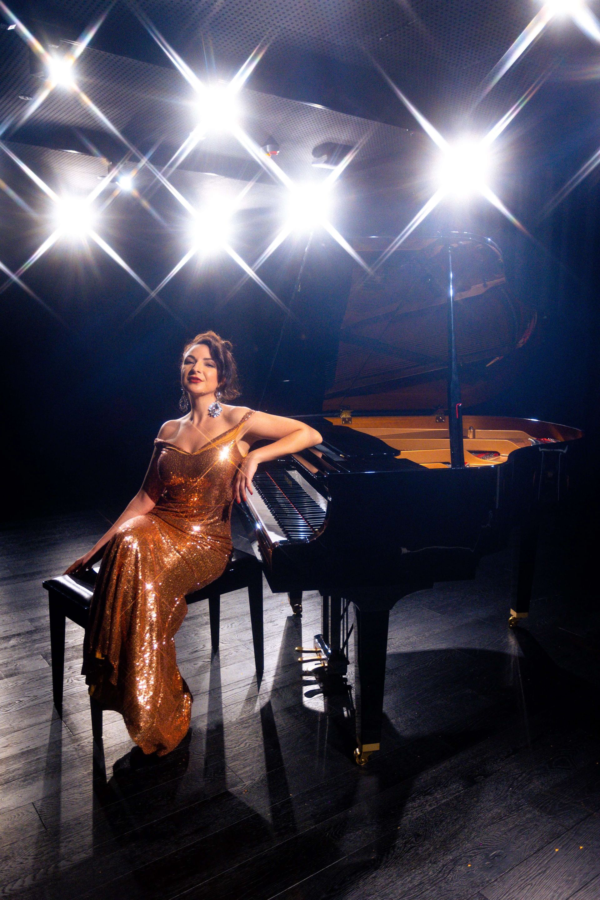 A person wearing headphones smiling behind a DJ deck at a table with lit candles and a shimmering silver fabric.