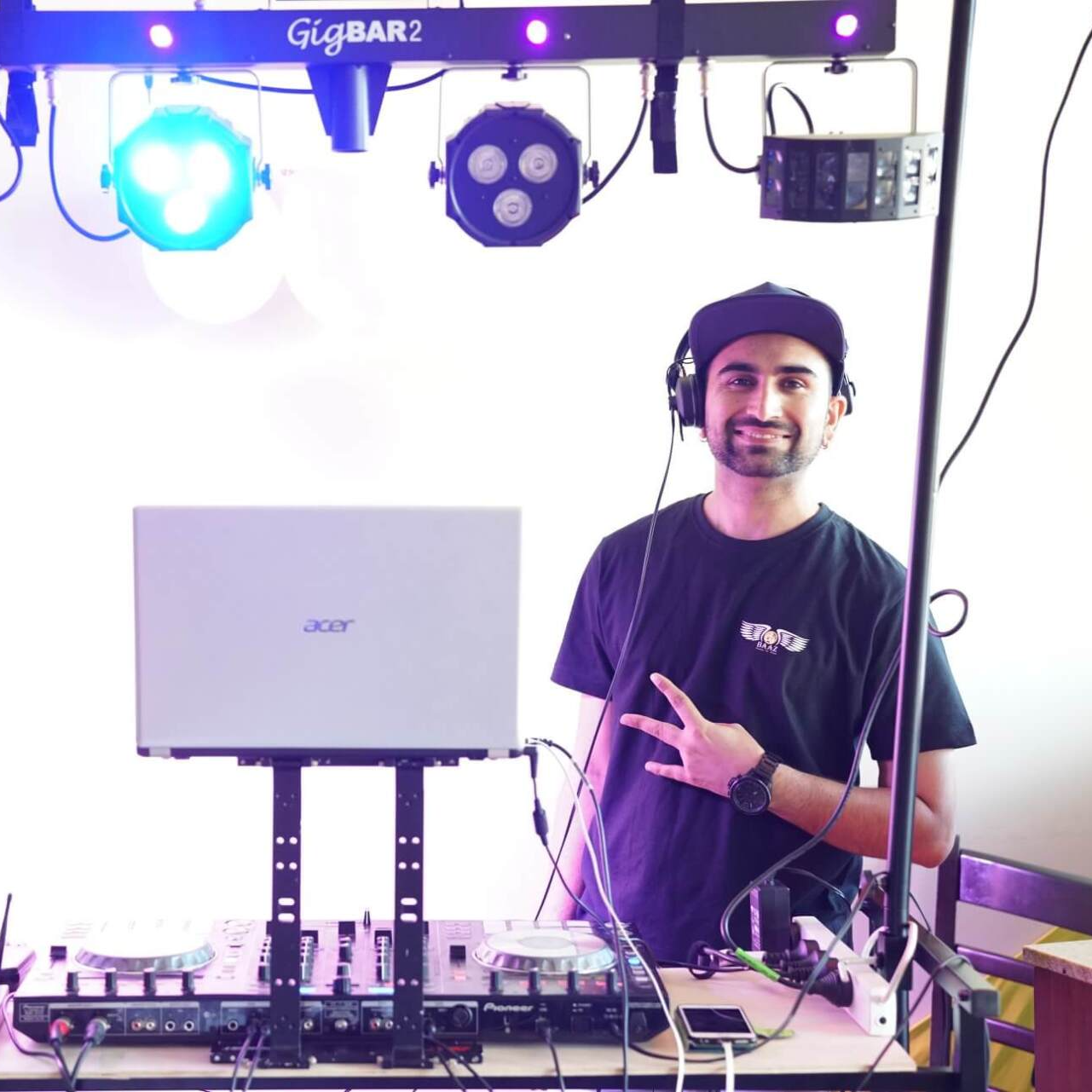 A man wearing headphones stands in front of an acer laptop