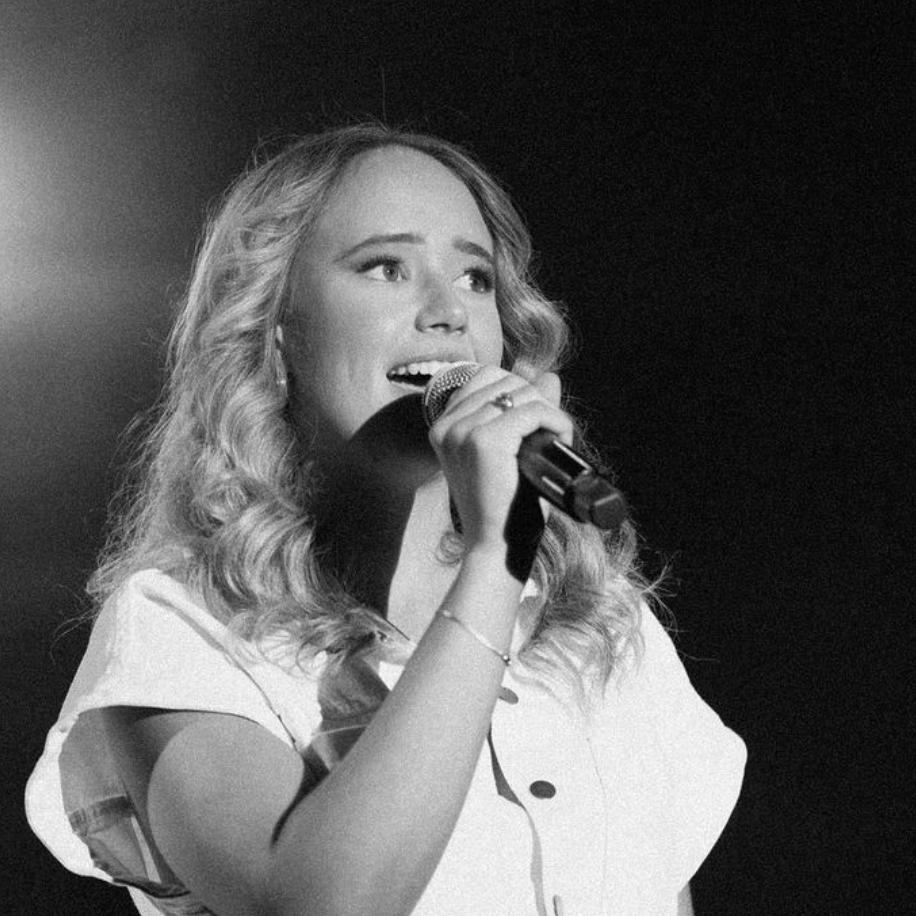 A woman is singing into a microphone in a black and white photo.