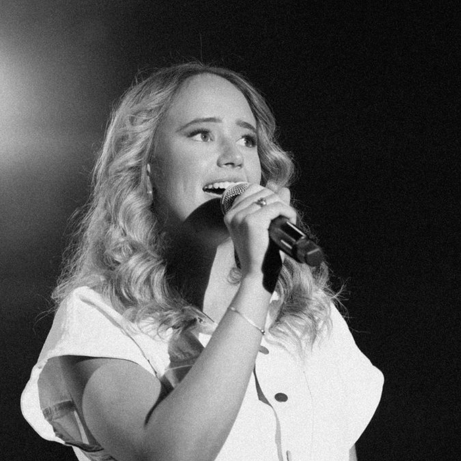 A woman is singing into a microphone in a black and white photo.