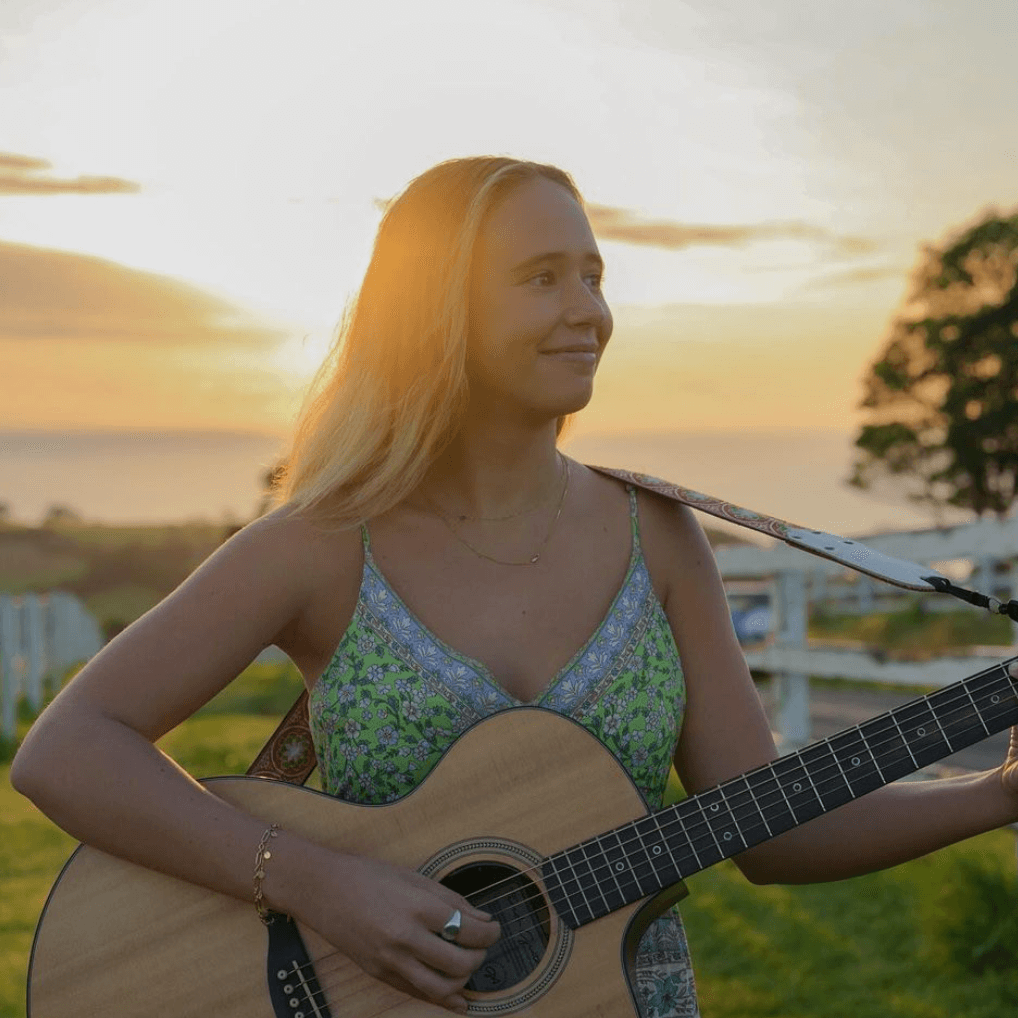 A woman in a green dress is playing an acoustic guitar