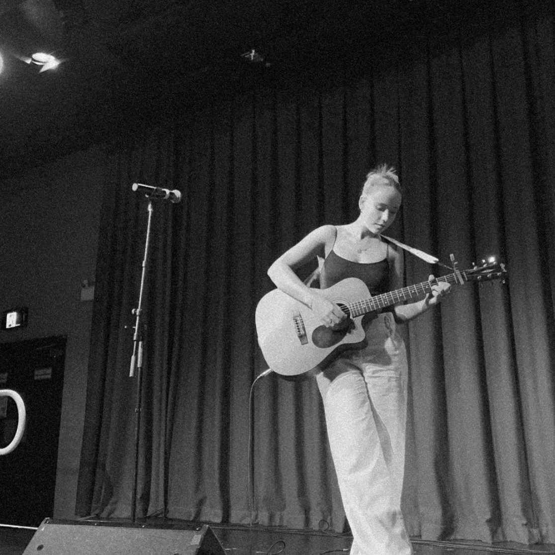 A woman singing into a microphone while playing a guitar