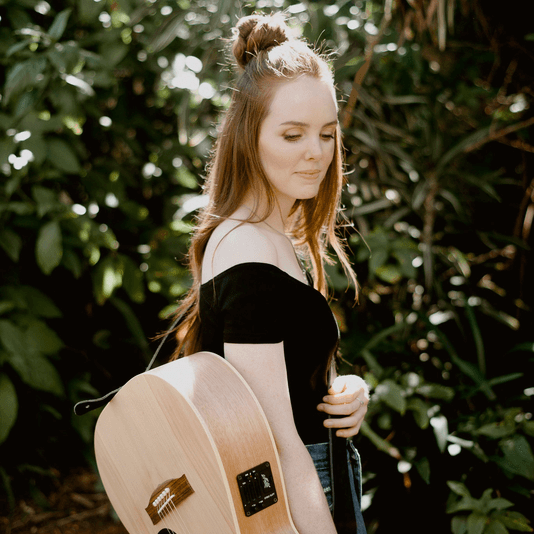 A woman in a black top is holding a guitar.