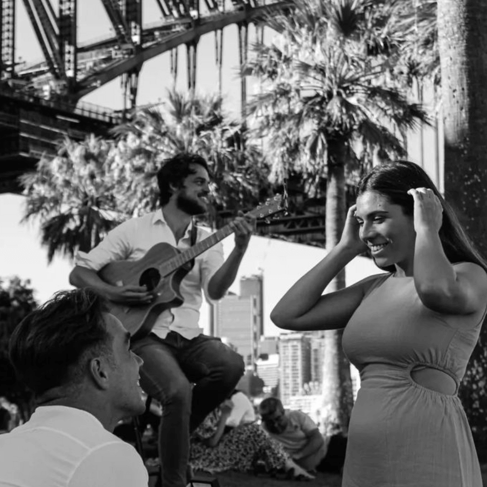 A man is playing a guitar in front of a woman.