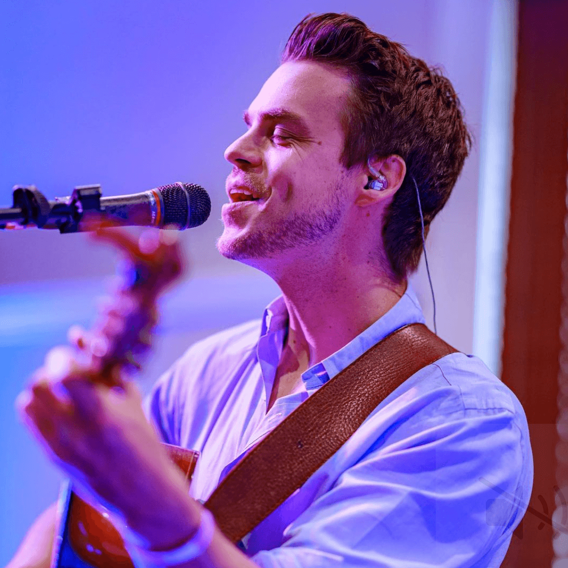 A man singing into a microphone while playing a guitar