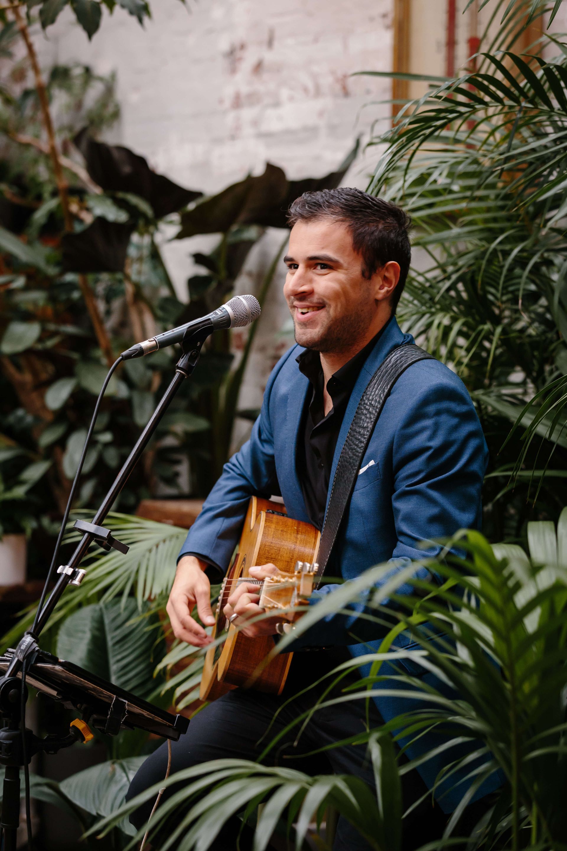 A man in a blue suit is playing a guitar and singing into a microphone.