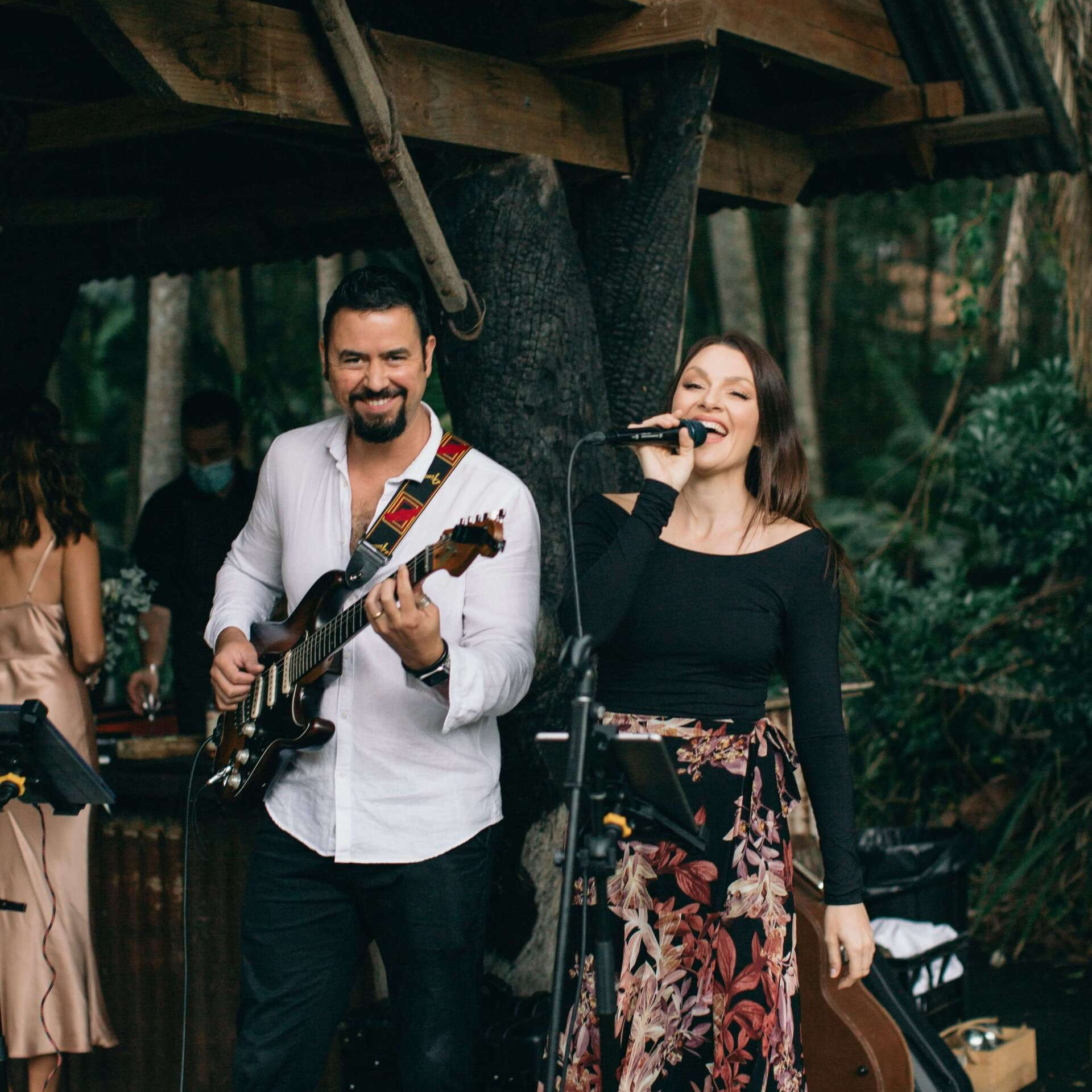 A man is playing a guitar and a woman is singing into a microphone.