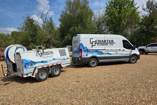 A white van with a trailer attached to it is parked in a gravel lot.