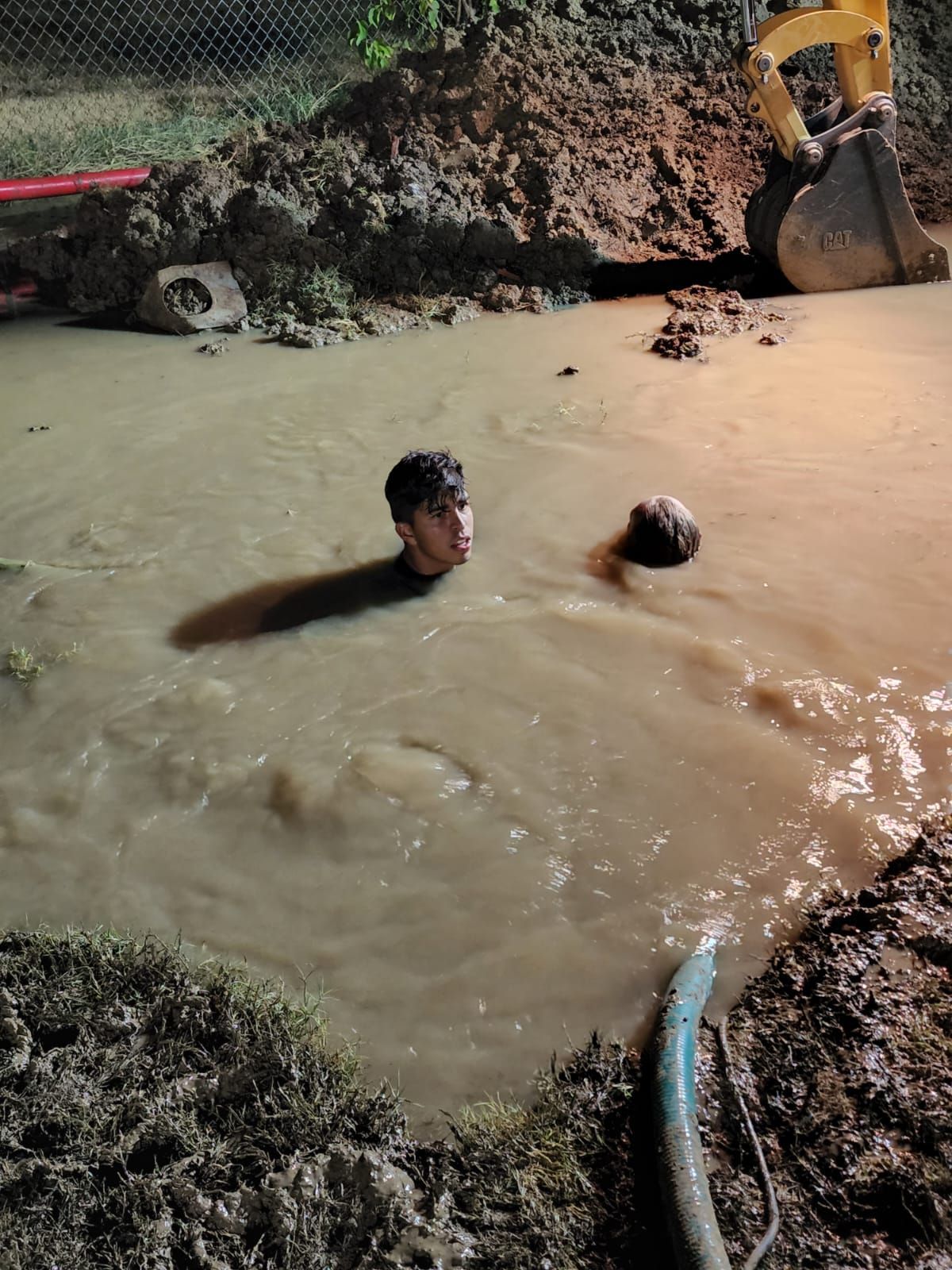 A man is swimming in a puddle of water next to a bulldozer.