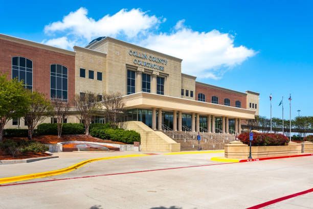 A large building with stairs leading up to it and a parking lot in front of it.