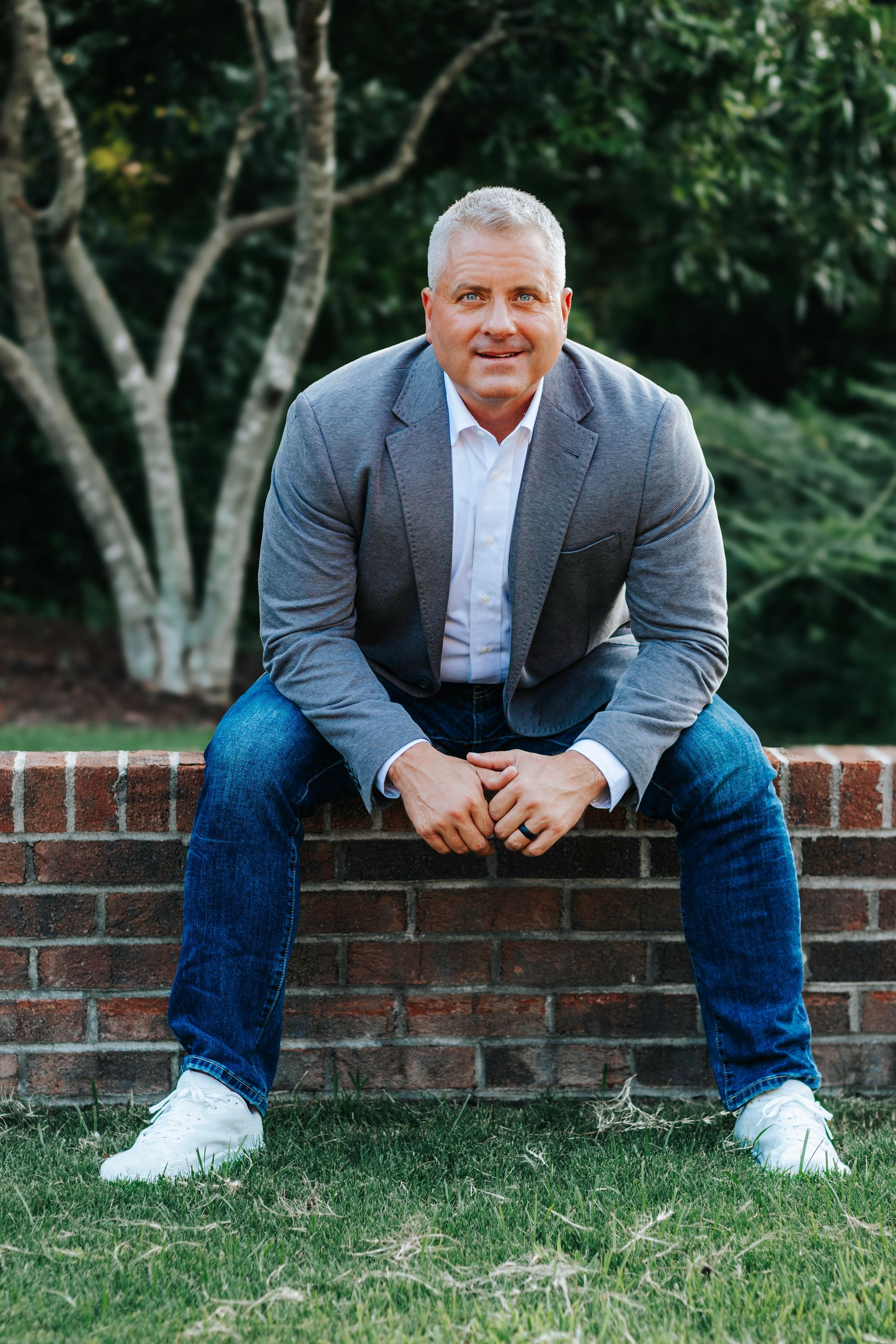 A woman is sitting at a desk with a laptop and a vase of flowers.