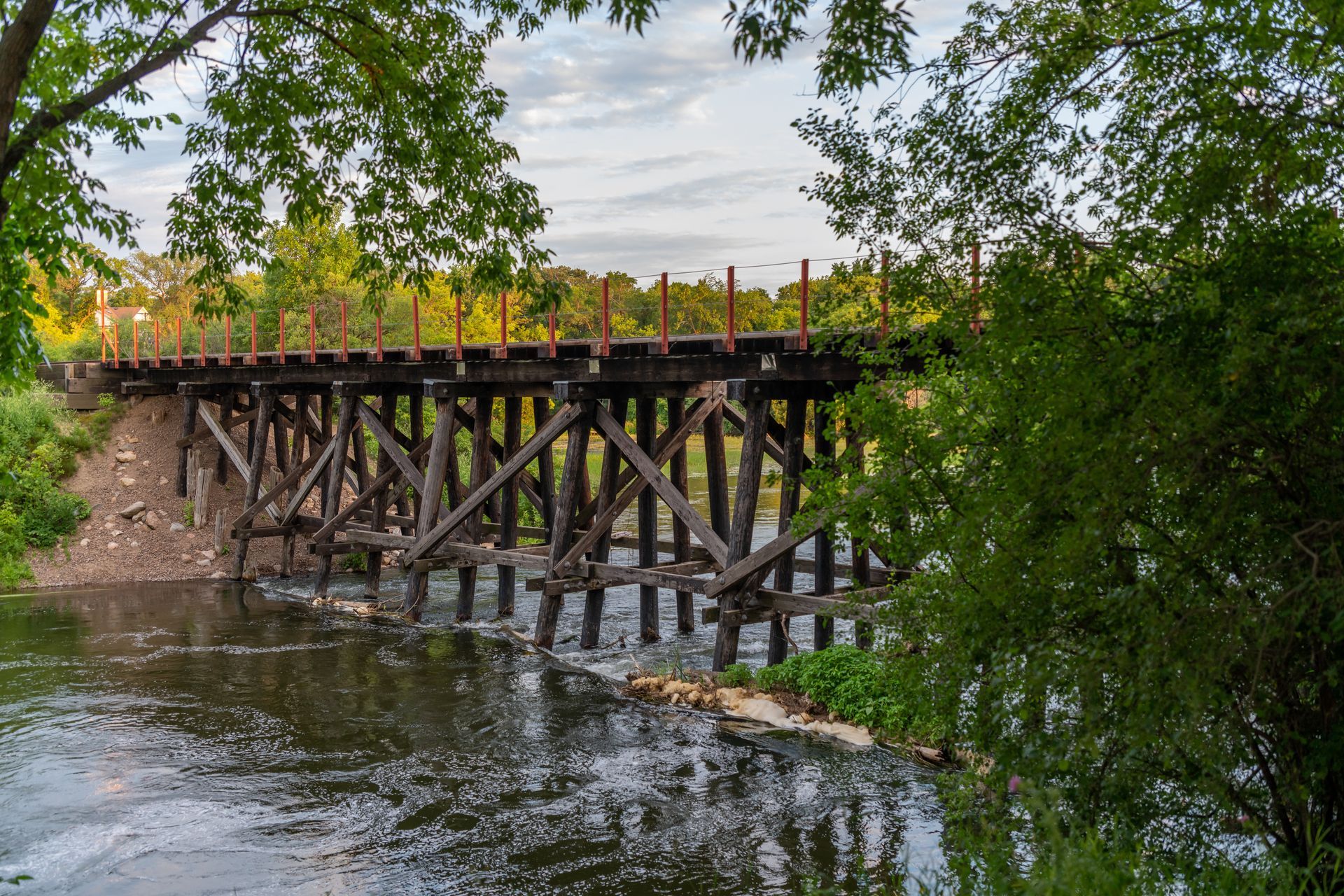 A wooden bridge over a river surrounded by trees.