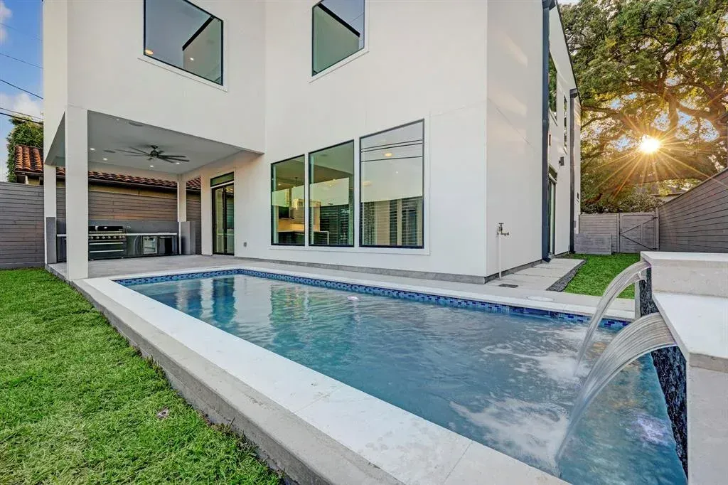 There is a large swimming pool in the backyard of a house.