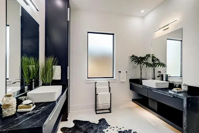 A bathroom with two sinks , a mirror and a window.