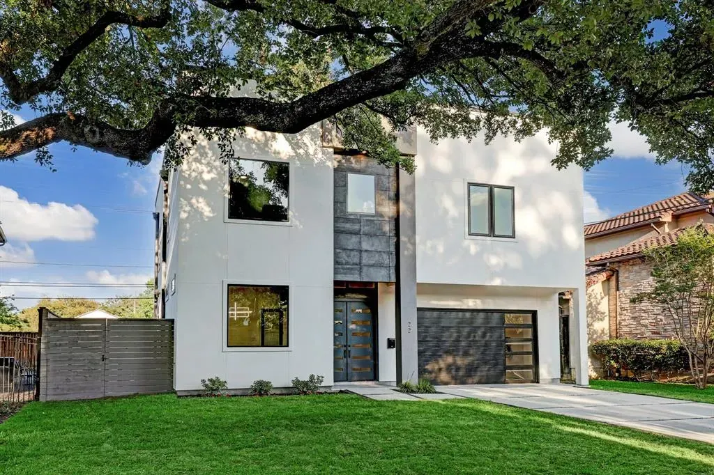 A white house with a black garage door is sitting on top of a lush green lawn.
