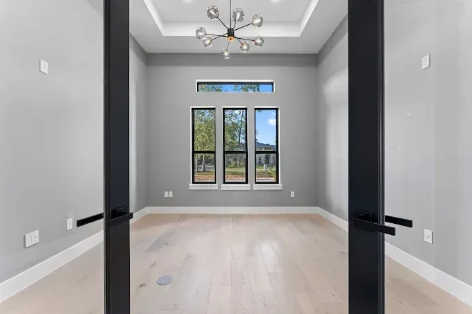 An empty room with hardwood floors and three windows.