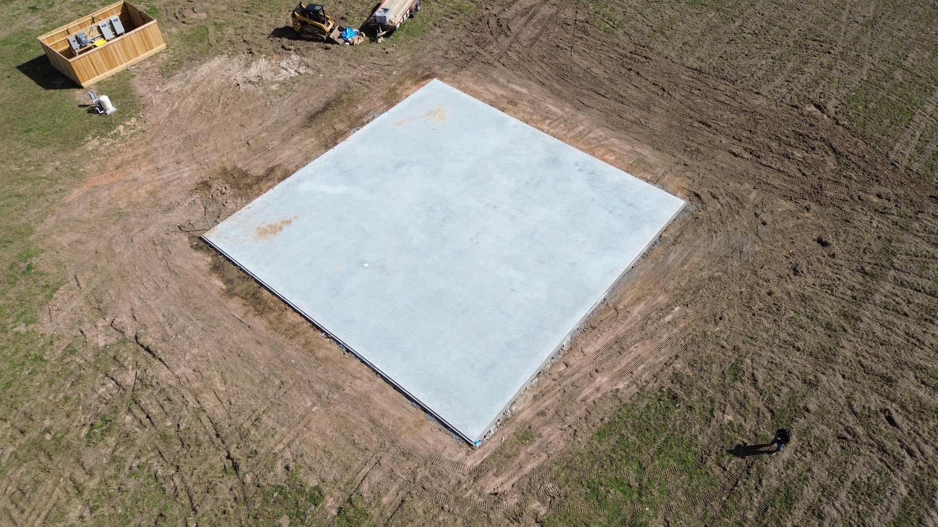 An aerial view of a large square concrete slab in a field.