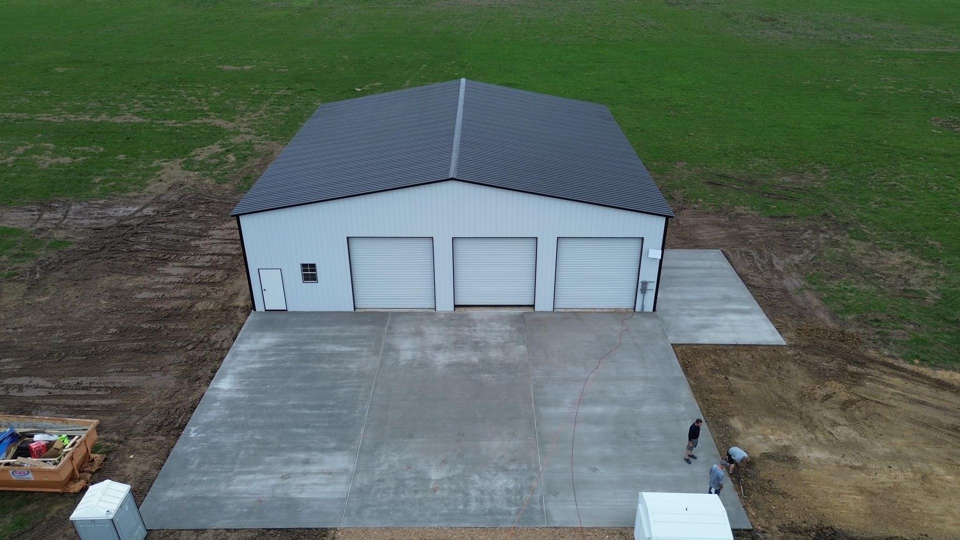 An aerial view of a garage and driveway in a field.