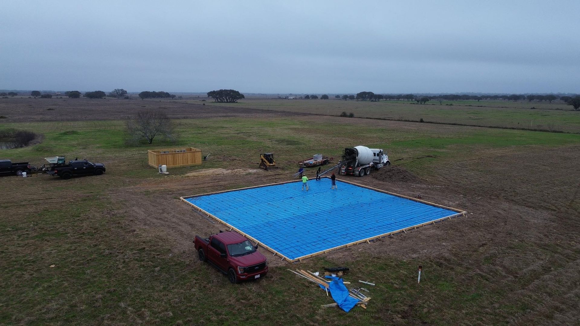 An aerial view of a large blue tarp in the middle of a field.