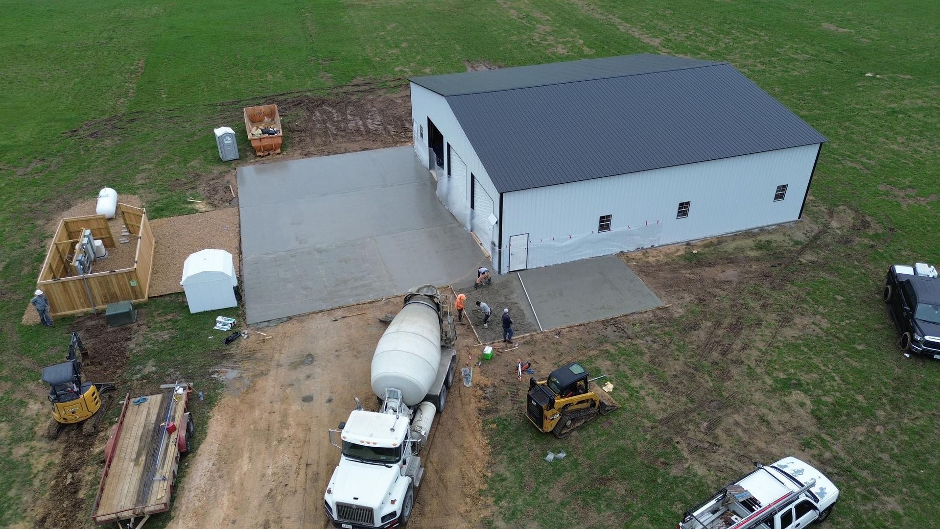 An aerial view of a building under construction with a concrete mixer in front of it.