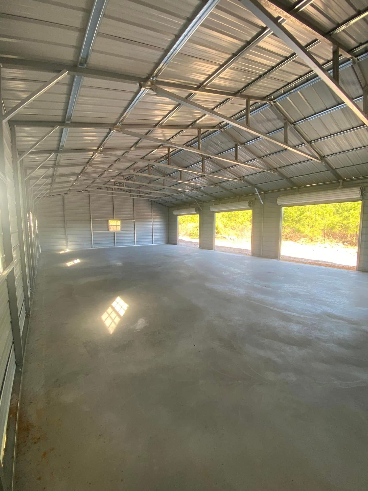 A large empty warehouse with a metal roof and concrete floor.