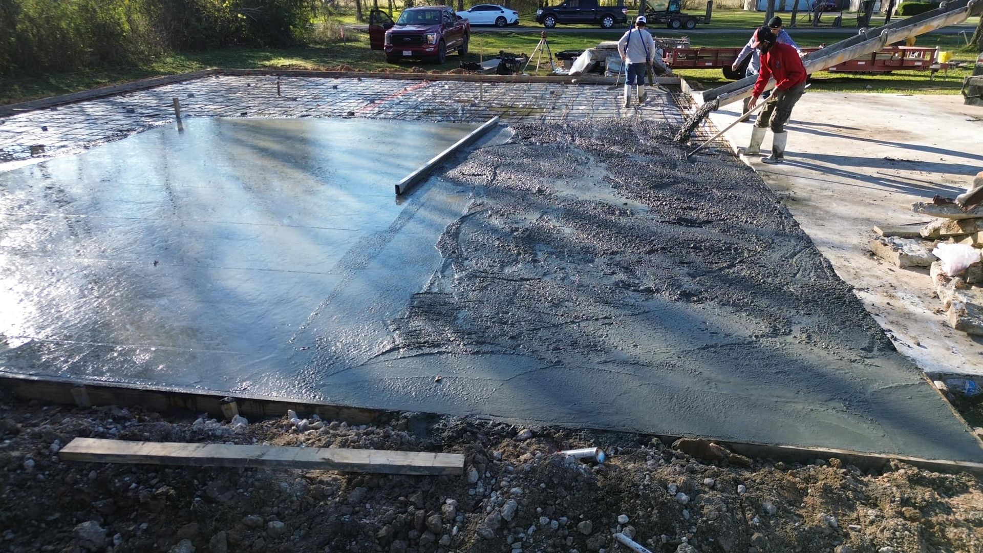 A group of people are working on a concrete driveway.