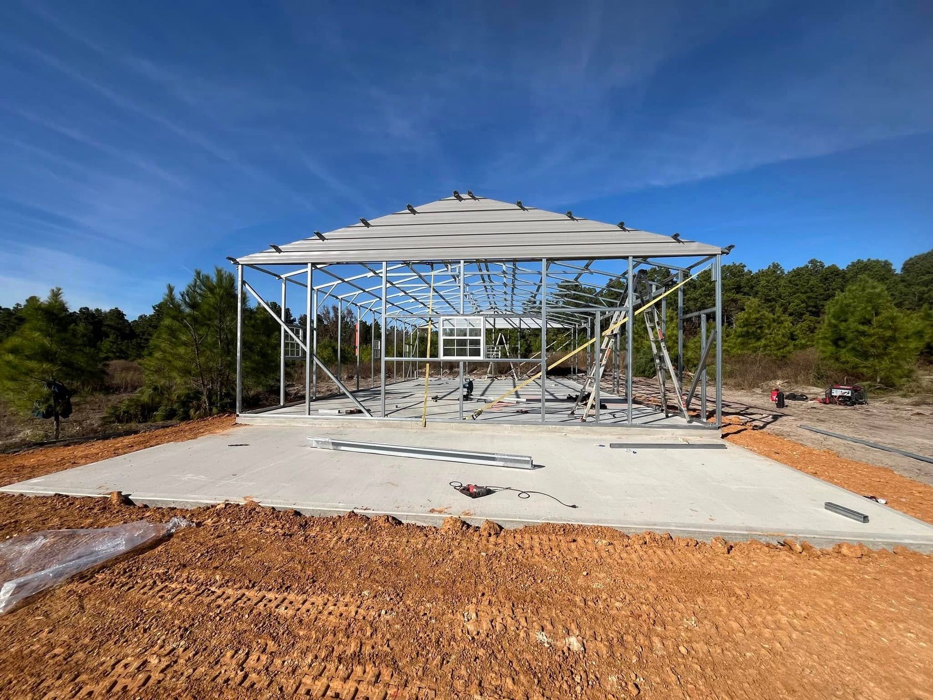 A metal structure is being built in the middle of a dirt field.