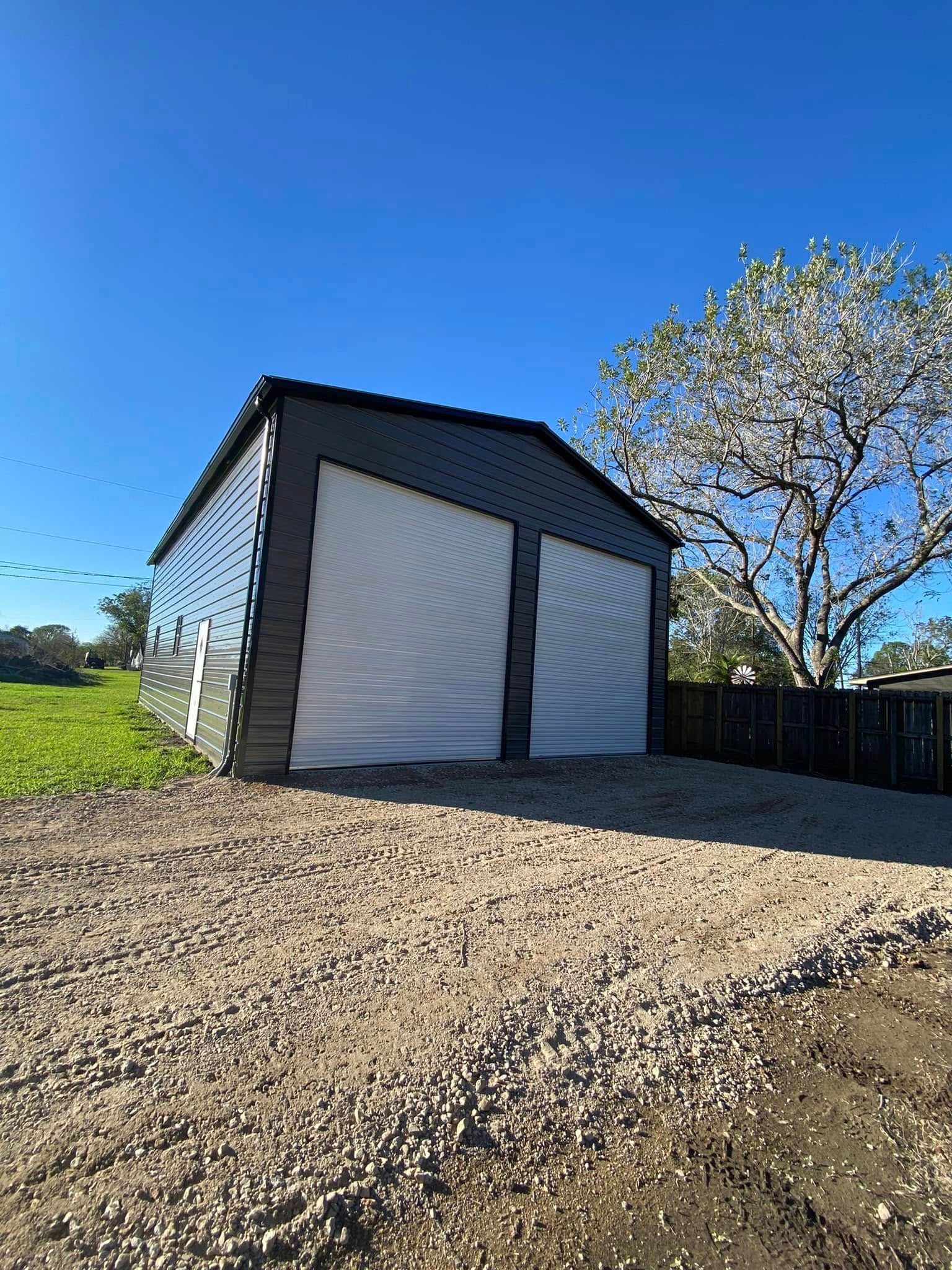 A garage with two white doors is sitting on top of a gravel lot.