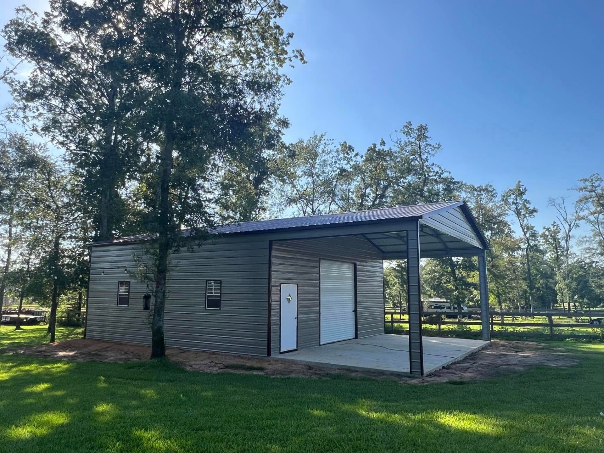 A garage with a white door is in the middle of a grassy field.
