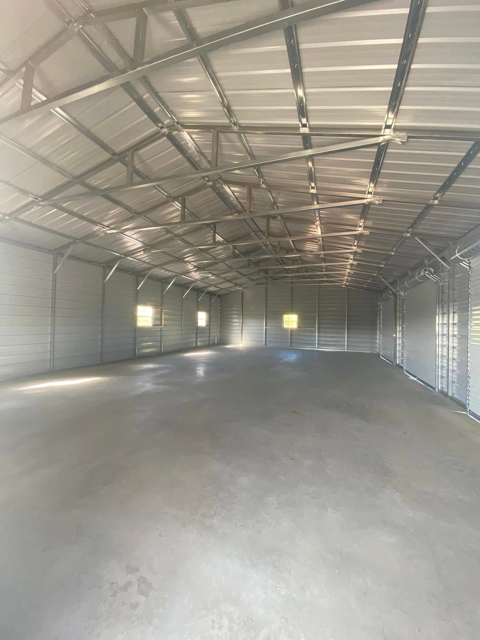 A large empty warehouse with a metal roof and concrete floor.