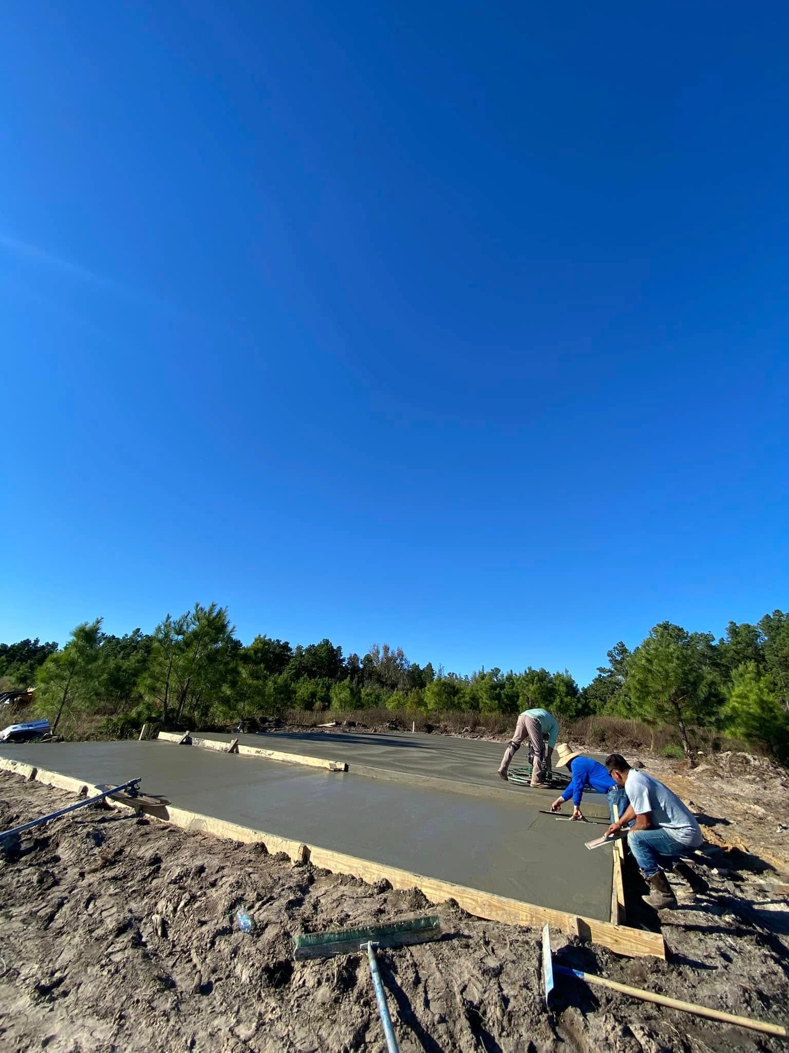 A group of construction workers are working on a concrete driveway.