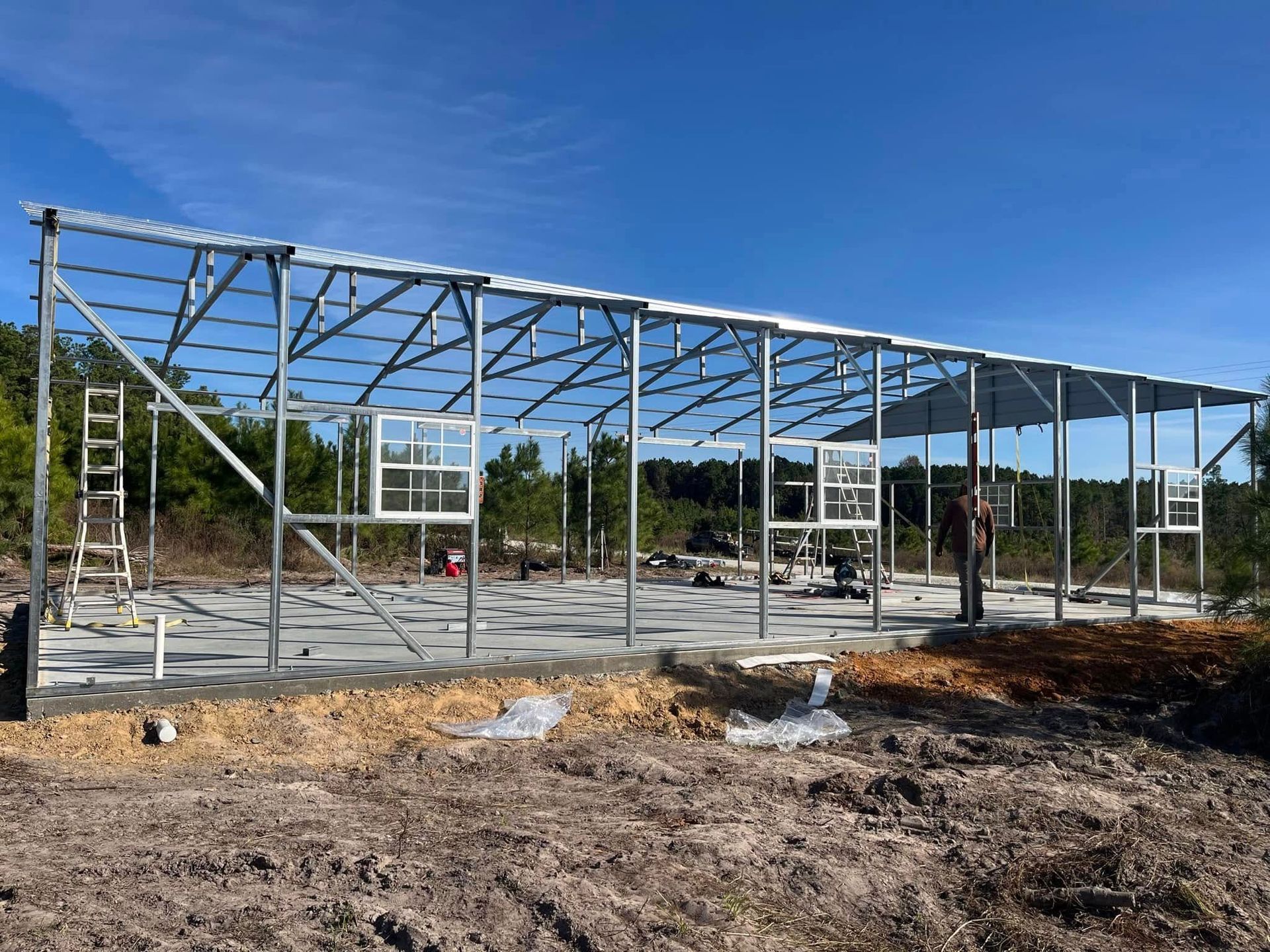 A large metal structure is being built in a dirt field.