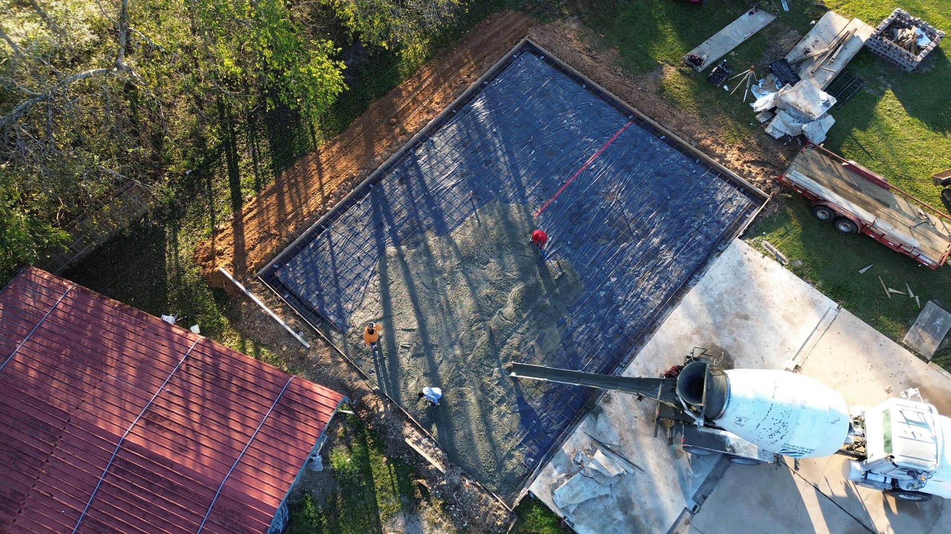 An aerial view of a concrete foundation being poured into a driveway.