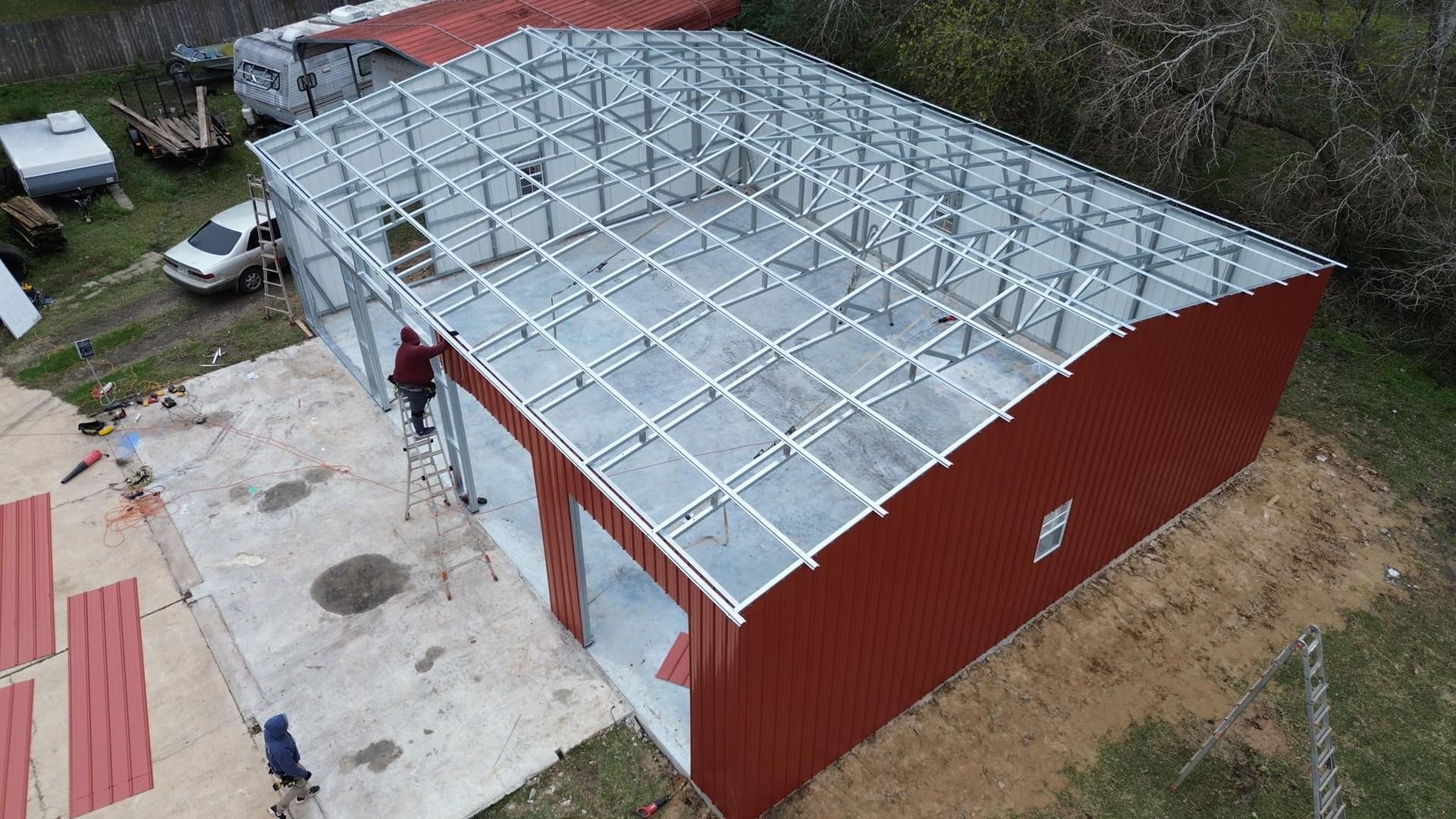 An aerial view of a red metal building under construction.