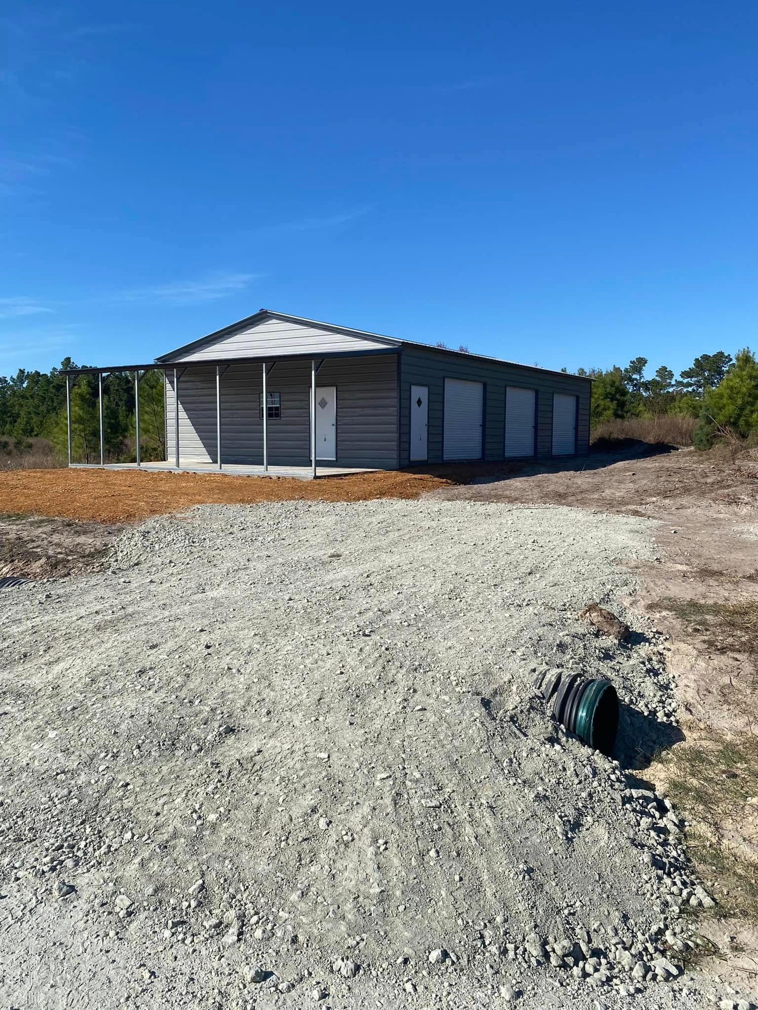 A large metal building is sitting on top of a gravel lot.