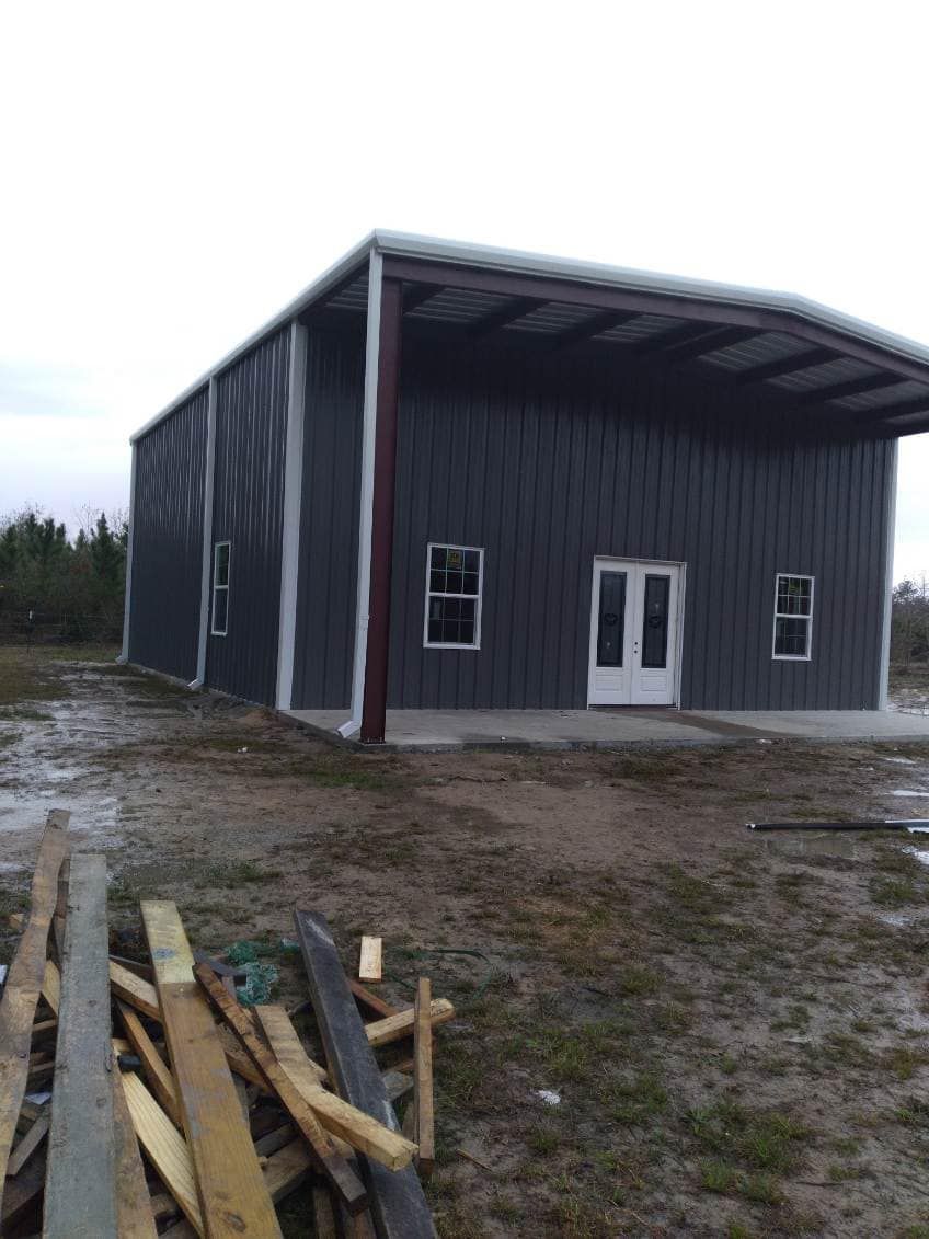 A large metal building is sitting in the middle of a dirt field.