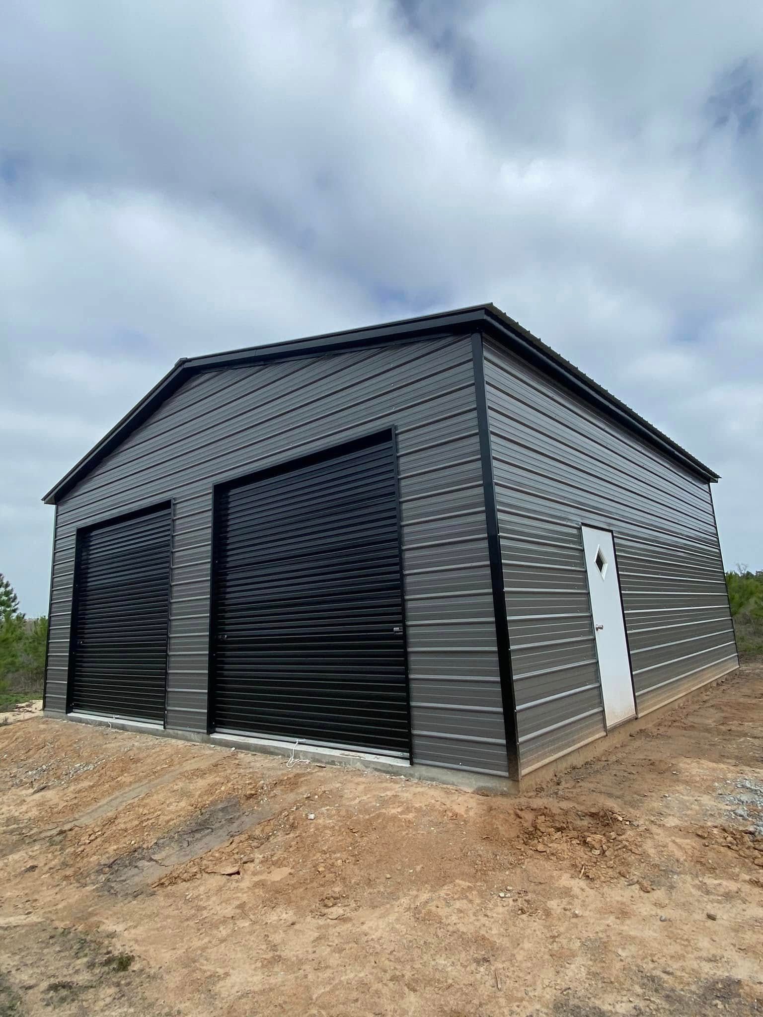 A metal garage with two garage doors is sitting on top of a dirt hill.