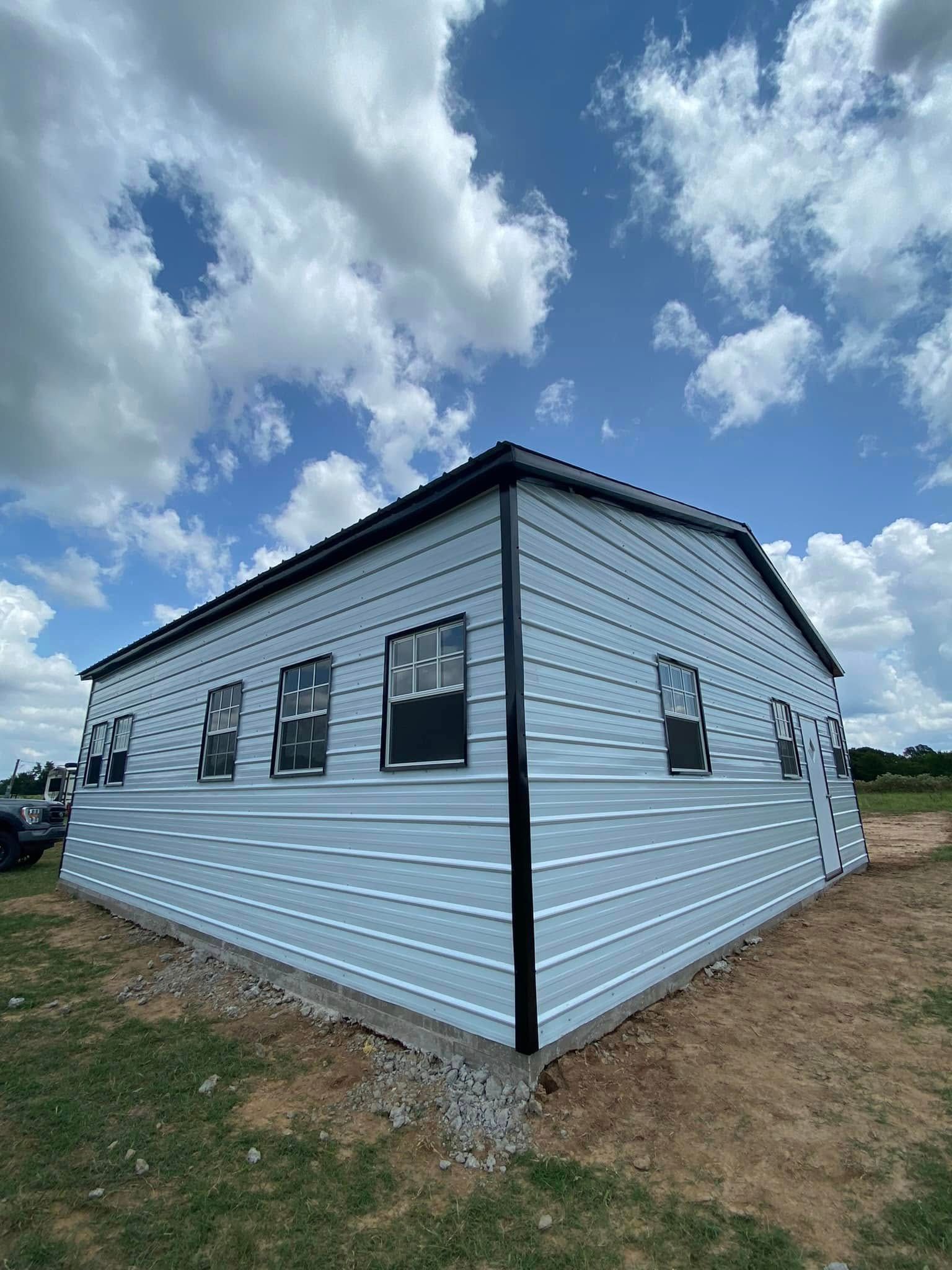 A white house with a lot of windows is sitting in the middle of a field.