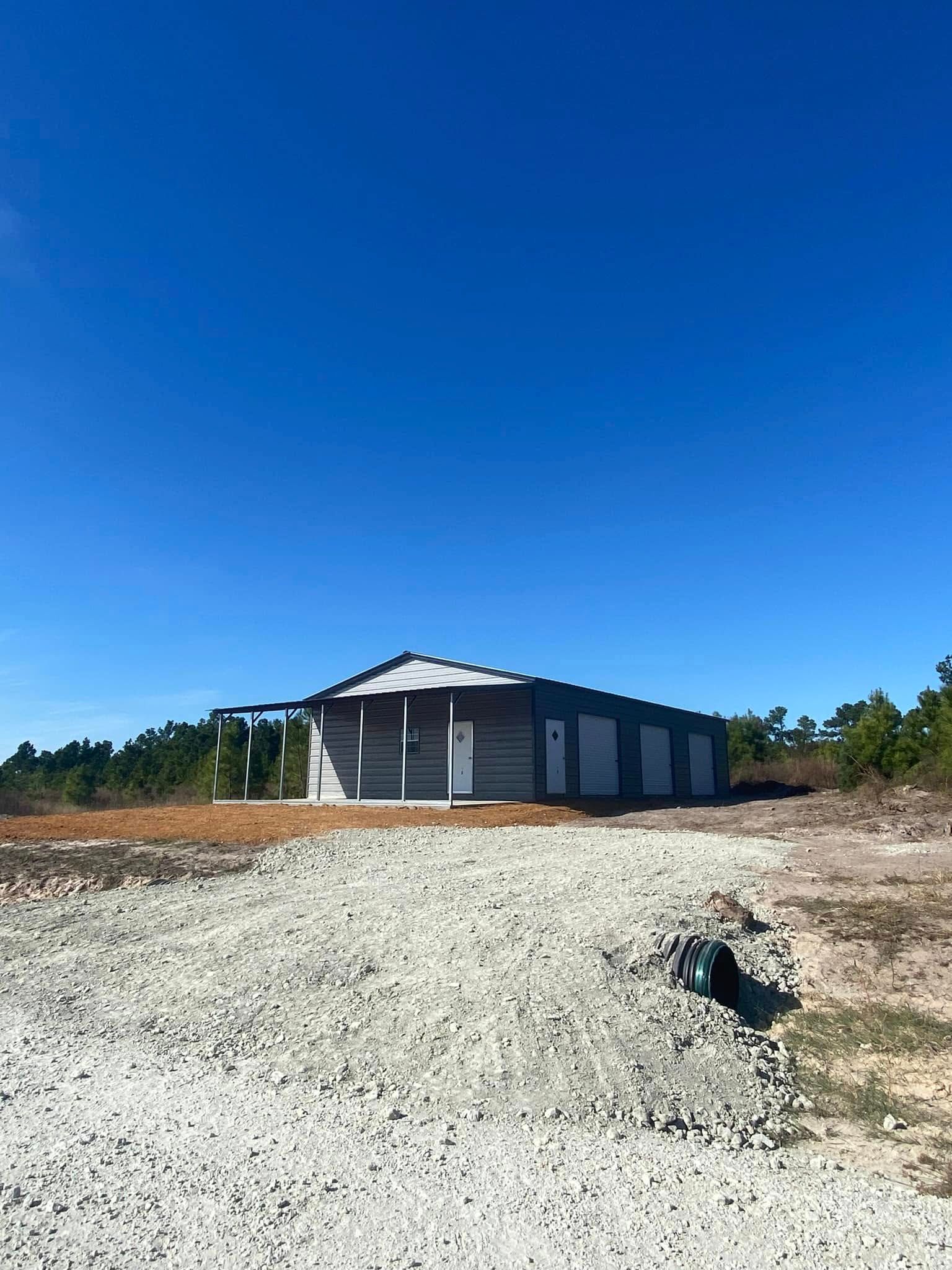 A small house is sitting in the middle of a dirt field.