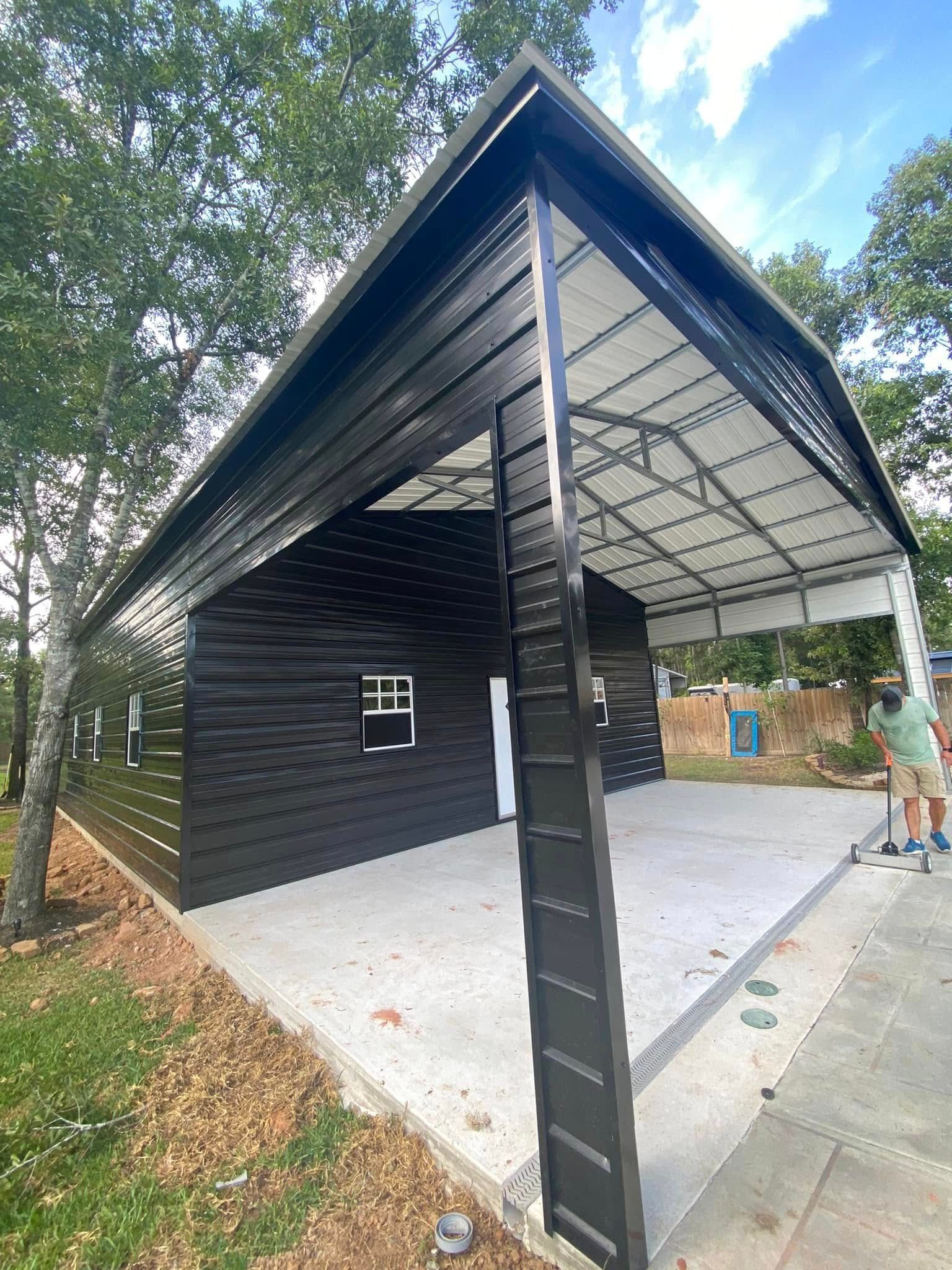 A man is standing in front of a black garage with a white roof.