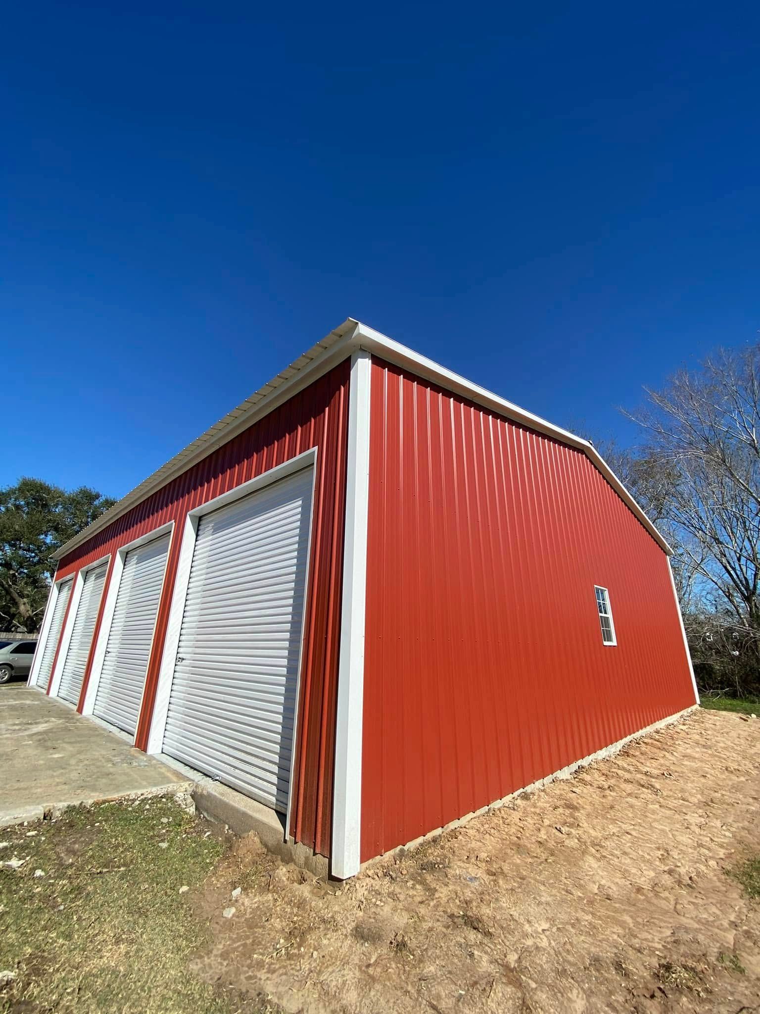 A red barn with white doors and a blue sky in the background.