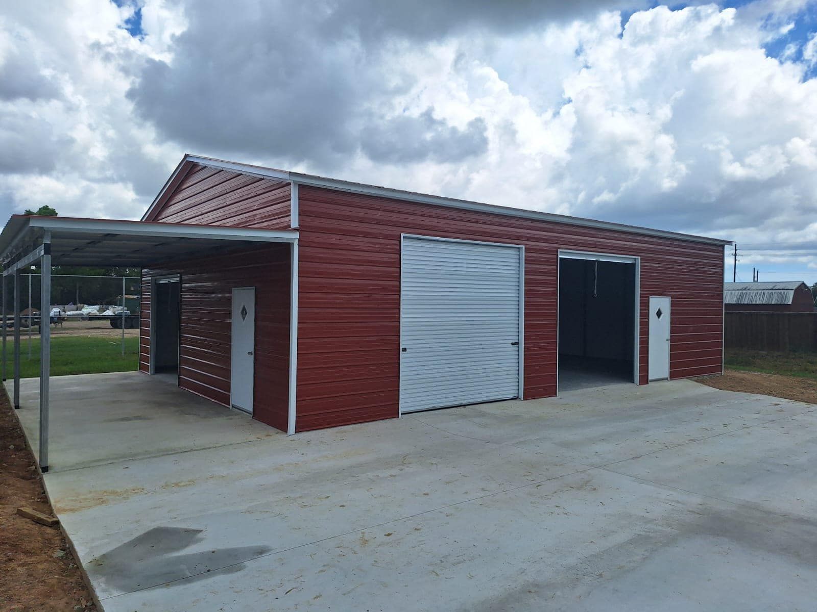 A red garage with a white garage door and a carport.