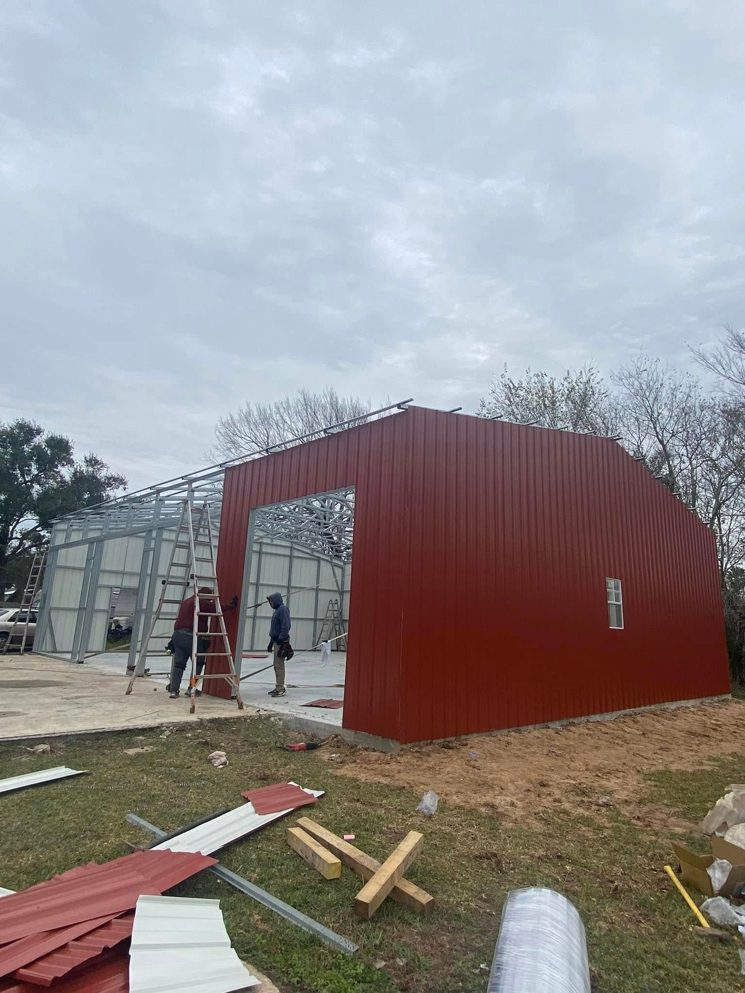 A red metal building is being built in a field.