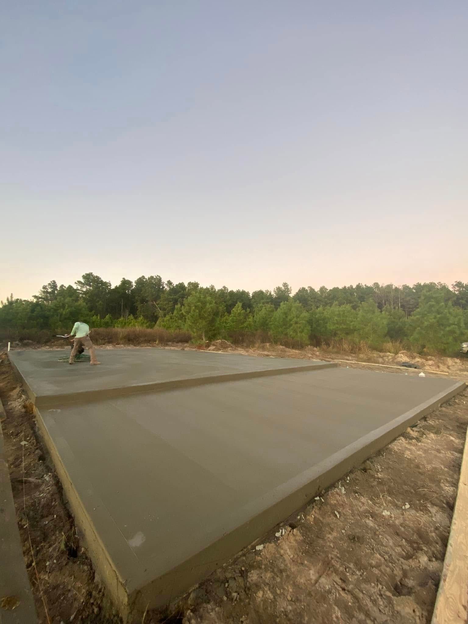 A man is working on a concrete slab in a field.