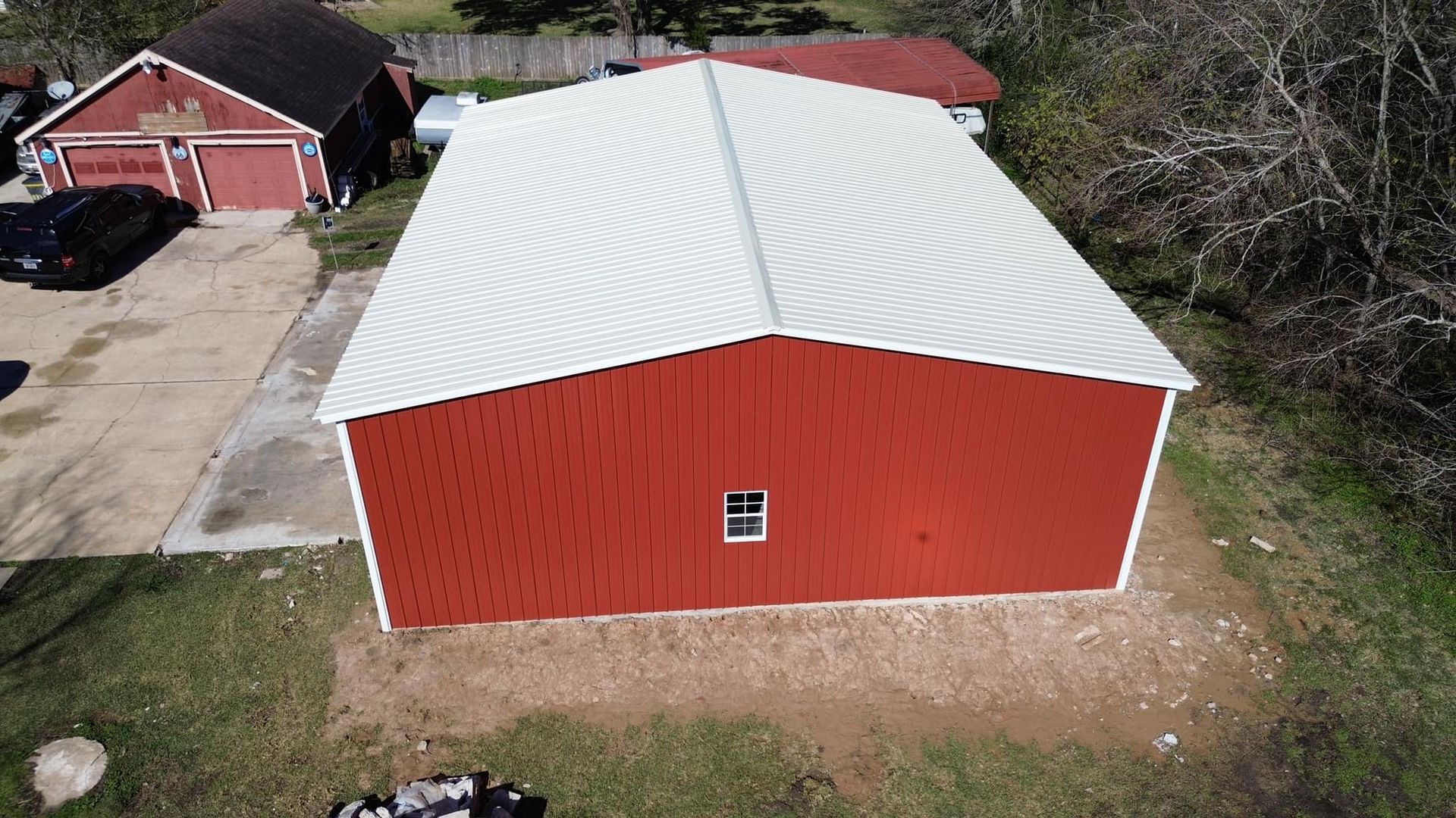 An aerial view of a red barn with a white roof.